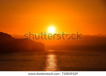 Sunrise over the headland from Funchal, Madeira. The sun emerges from over the Atlantic Ocean for at dawn