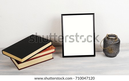 Photo frame on wooden table next to books. Decor.