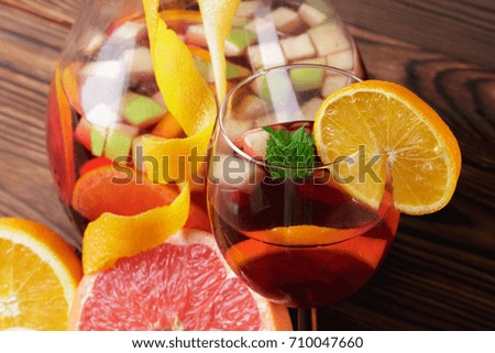 Closeup of a bright juicy grapefruit, a gall of refreshing beverage with strawberries and oranges, a jug of fruit drink, fresh green leave of mint on a wooden blurred background.