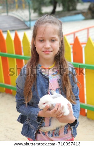 girl holding a white rabbit in hands
