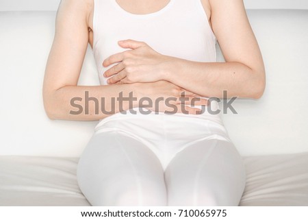 woman with windshield pain.Acute pain in a woman  chest . Female holding hand to spot of Under the breast. Concept photo with read spot indicating location of the pain.