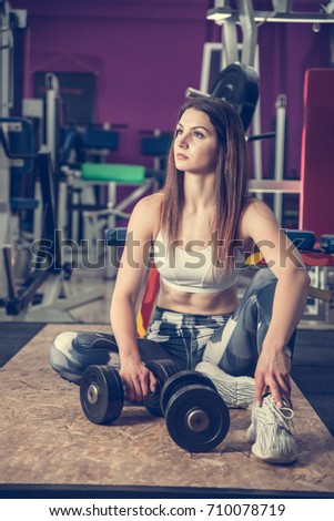 active young woman rests after workout in fitness club gym