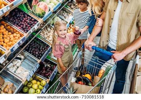 cropped shot of happy family with trolley shopping together in supermarket 