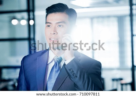 Young Asian businessman talking on a phone. Image with lens flare effect.