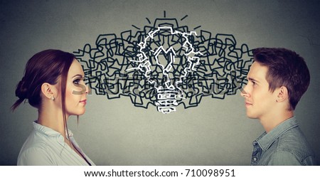 Young man and woman looking at each other exchanging their thoughts coming up together with an idea light bulb  Royalty-Free Stock Photo #710098951