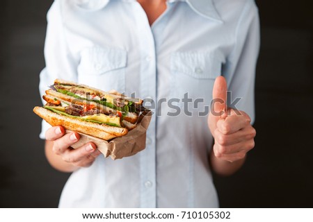 girl showing thumb holding a sandwich