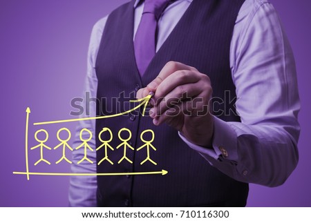 Shooting in the Studio .A businessman in a waistcoat ,shirt and tie on a purple background draw icons of people.The concept of population growth,fertility,population,workers
