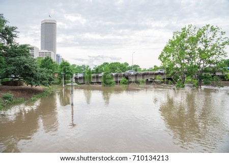 High and fast water rising in Bayou River under Montrose boulevard with near town Houston in background, cloud storm sky. Heavy rains from Harvey Tropical Hurricane storm caused many flood areas