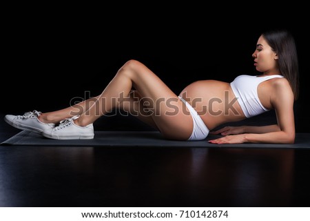 asian pregnant woman lying in white underwear, on black 