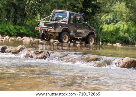 Stream flowing through the forest with off road car.