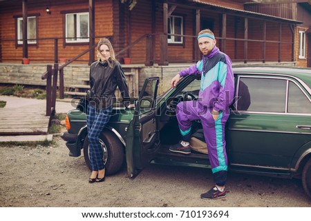 Guy and girl in clothes of the nineties, next to the old car Royalty-Free Stock Photo #710193694