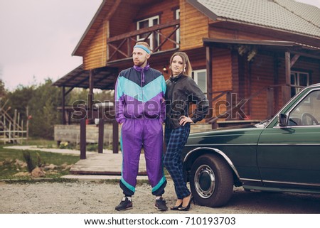 Guy and girl in clothes of the nineties, next to the old car Royalty-Free Stock Photo #710193703