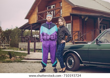 Guy and girl in clothes of the nineties, next to the old car Royalty-Free Stock Photo #710193724