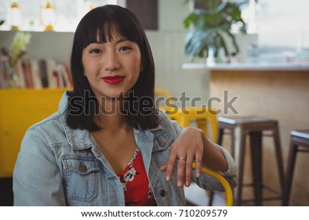 Portrait of young woman sitting on chair in cafe