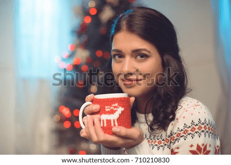 young woman with cup of hot drink on christmas