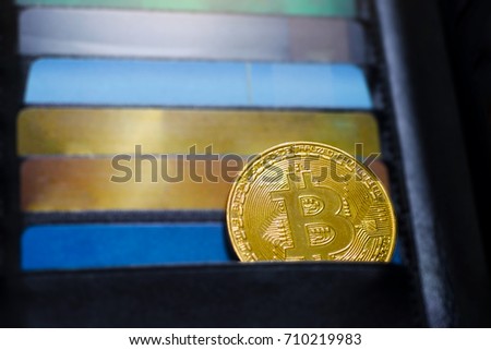 Photo of golden bitcoin (new virtual currency) with credit cards as a background.