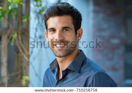 Handsome mid adult man smiling and looking at camera. Portrait of happy young casual man. Close up portrait of hispanic guy standing outdoor. Royalty-Free Stock Photo #710258758