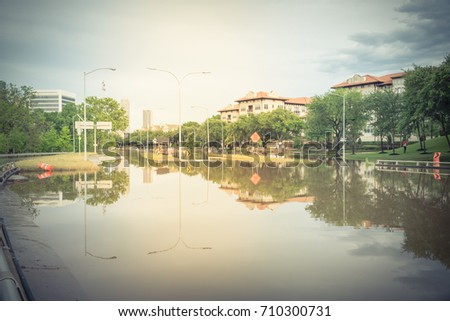 High water rising at Allen Parkway with road warning signs. Residential buildings and downtown Houston in background under cloudy sky. Heavy rains from storm cause many flood. Swamp car. Vintage tone