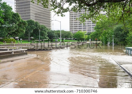 High and fast water rising in Bayou River from Montrose boulevard with near town Houston in background, cloud sky. Heavy rains from Tropical Hurricane storm caused many flood in greater Houston areas