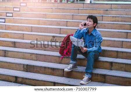 young handsome man stand on stair and serious talking on smartphone which looking up to sky. outdoor working.