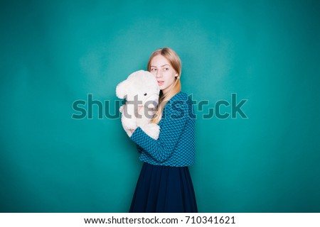 high smiling girl with soft toy posing in a photo Studio. emotional portrait. long hair and troubled skin