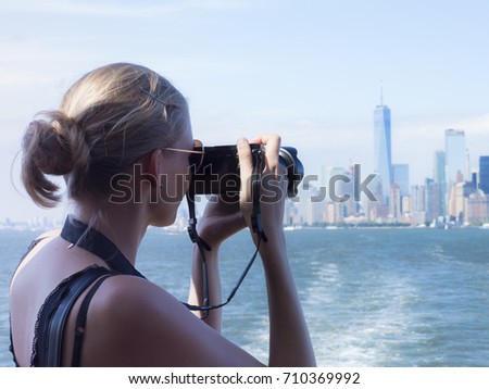 Woman taking photo of the NYC skyline from a boat