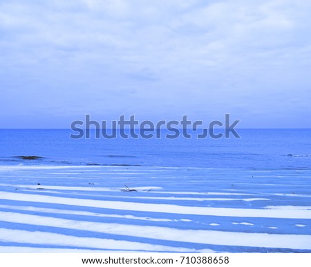 View through beach sand with snow on the sea. Winter landscape
