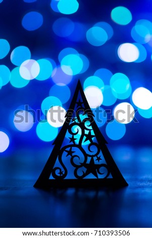 Silhouette of Christmas tree with starry ornament with garland lights on blue bokeh background