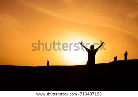 Inspired motivated person raise his hands towards the setting sun against the background of an orange sky Royalty-Free Stock Photo #710407153