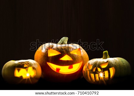 Three brightly glowing pumpkins on a dark background. Picture for decoration on the holiday of Halloween.