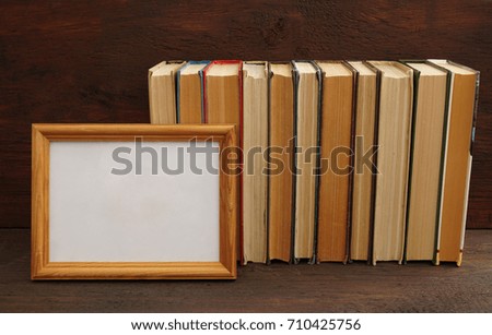 Old books on the shelf and blank picture empty frame for inscription. back to school  idea.           