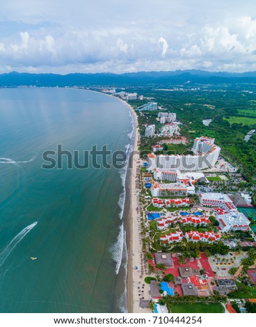 A vertical, aerial panoramic picture of Nuevo Vallarta, Mexico. This image may feature Nuevo Vallarta's beach, ocean, water channel, and it's hotel row.