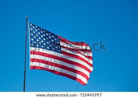American Flag waving in the wind with a blue sky.