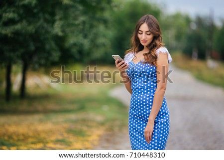 Portrait of woman with smart phone. Cropped image of young pretty trendy girl  posing outdoors using mobile phone.