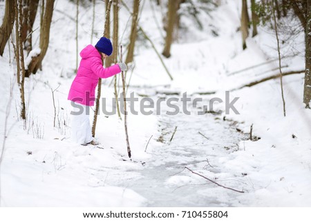 Adorable little girl having fun in beautiful winter park. Cute child playing in a snow. Winter activities for kids.