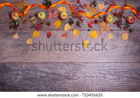 Autumn arrangement of leaves, apples and berries on a wooden background with free space for text. Top view, flat lay, copy space, season concept, toned retro effect