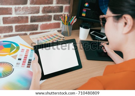 back view of professional young woman designer using mobile digital tablet pad working with blank screen and designing graphic product. selective focus photo.