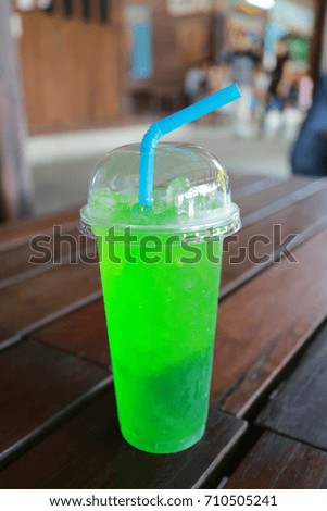 Green soda soft drink in glass on the food table.
