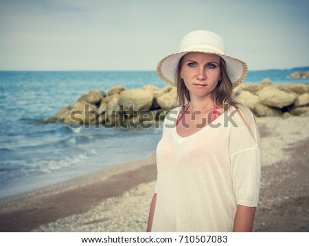 Beautiful middle-aged woman in hat on the beach. The concept of relaxing on the beach.