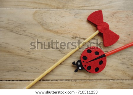 Top or flat lay view of Photo booth props a red ladybird and a red bow tie on a wooden background flat lay. Birthday parties and weddings.