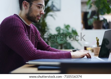 Cropped image of young IT programmer in eye glasses chatting with customer while developing business startup project using application on laptop computer connected to internet during distant work