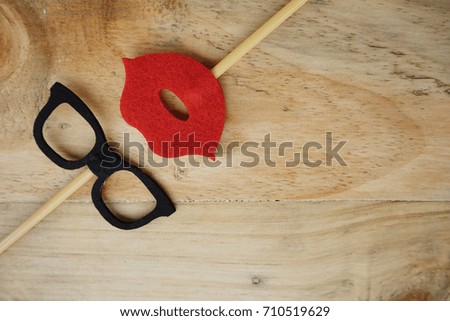 Top or flat lay view of Photo booth props a red lips and a black spectacles on a wooden background flat lay. Birthday parties and weddings.