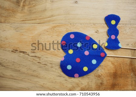 Top or flat lay view of Photo booth props a blue polkadot bow tie and a blue polkadot heart shape on a wooden background flat lay. Birthday parties and weddings.