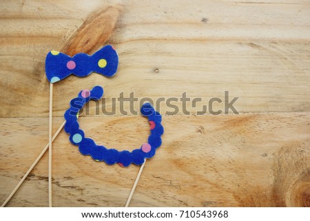 Top or flat lay view of Photo booth props a blue polkadot bow tie and a blue polkadot necklace on a wooden background flat lay. Birthday parties and weddings.