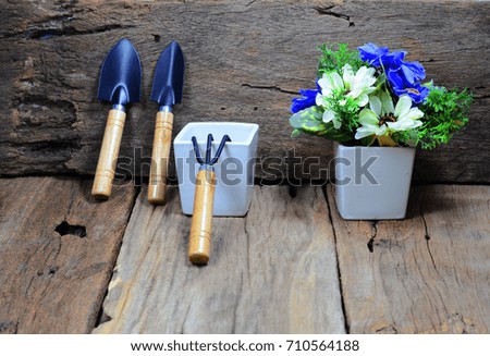 spoons  for gardening leaning against with old wood,a fork be with potted,white vase with blue and white flower on old wooden table