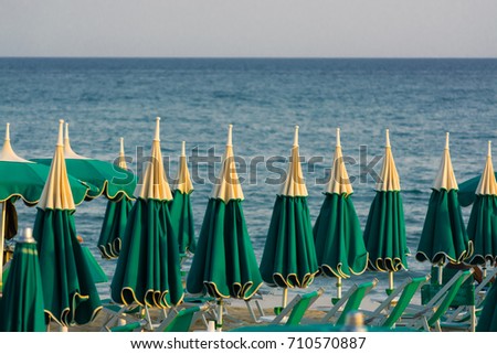 Vacation season - many beach umbrellas on the sea beach, holidays on the sea sunset