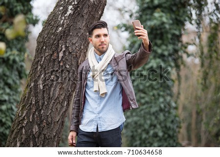 Athletic young man walking in the nature doing selfie