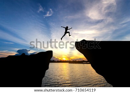 Man jump through the gap between hill.man jumping over cliff Royalty-Free Stock Photo #710654119