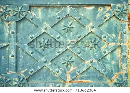 close up view of the old green rusty medieval metal door with rhombus pattern with stars and rivets as a background.