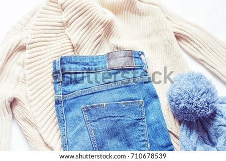 Beige cardigan, blue jeans and woolen knitted hat. Women's clothes combination. Trendy wear. Flat lay autumn or winter clothing. Casual style apparel